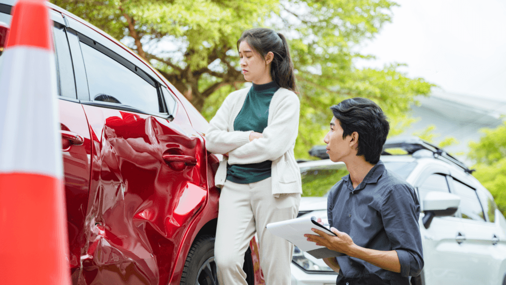 Damaged sedan beside a person with a clipboard