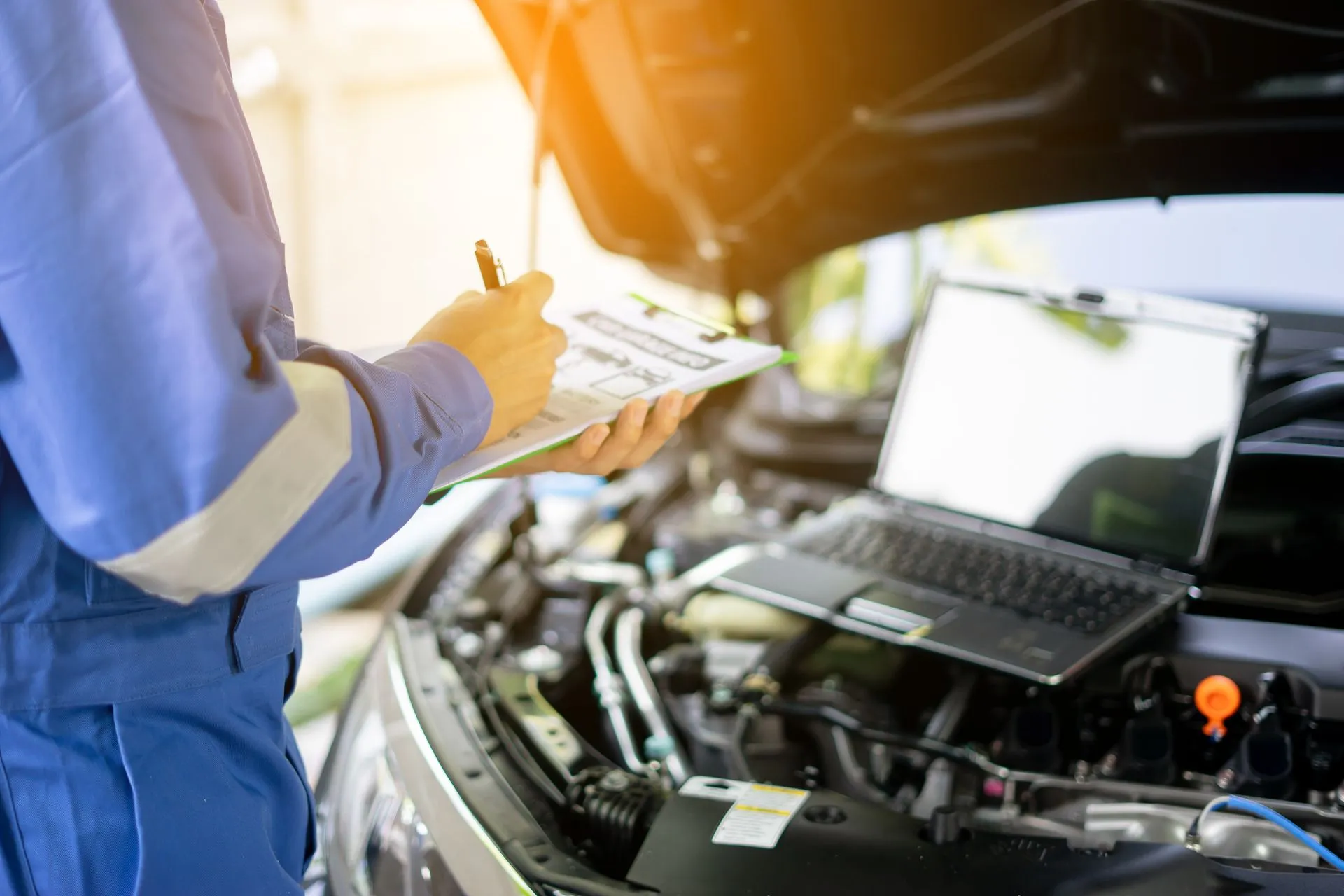 Technician with a clipboard over an engine bay
